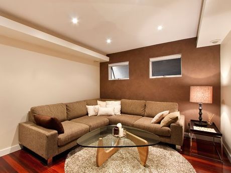 A living space with a brown sectional couch and a glass coffee table