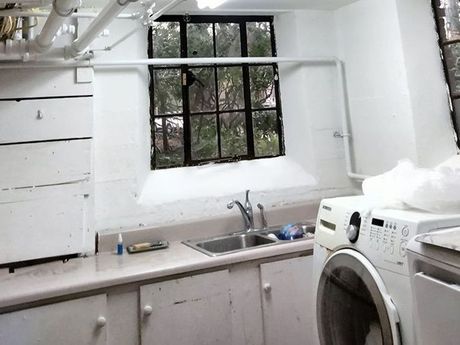 A laundry room with a washer and dryer, sink, and window.