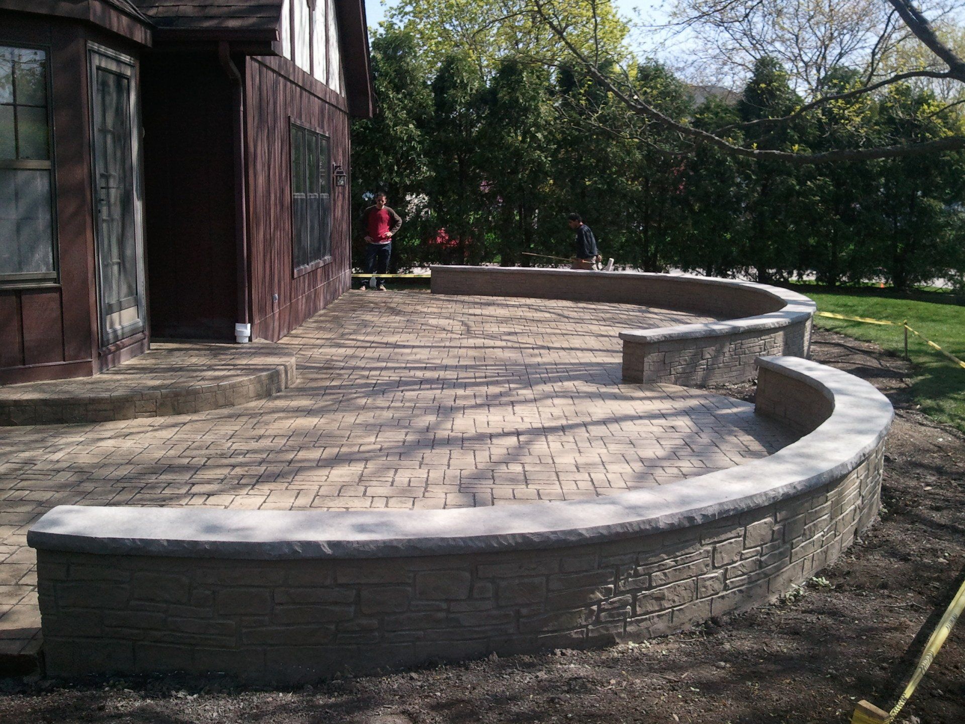 a brick patio with a curved wall in front of a house