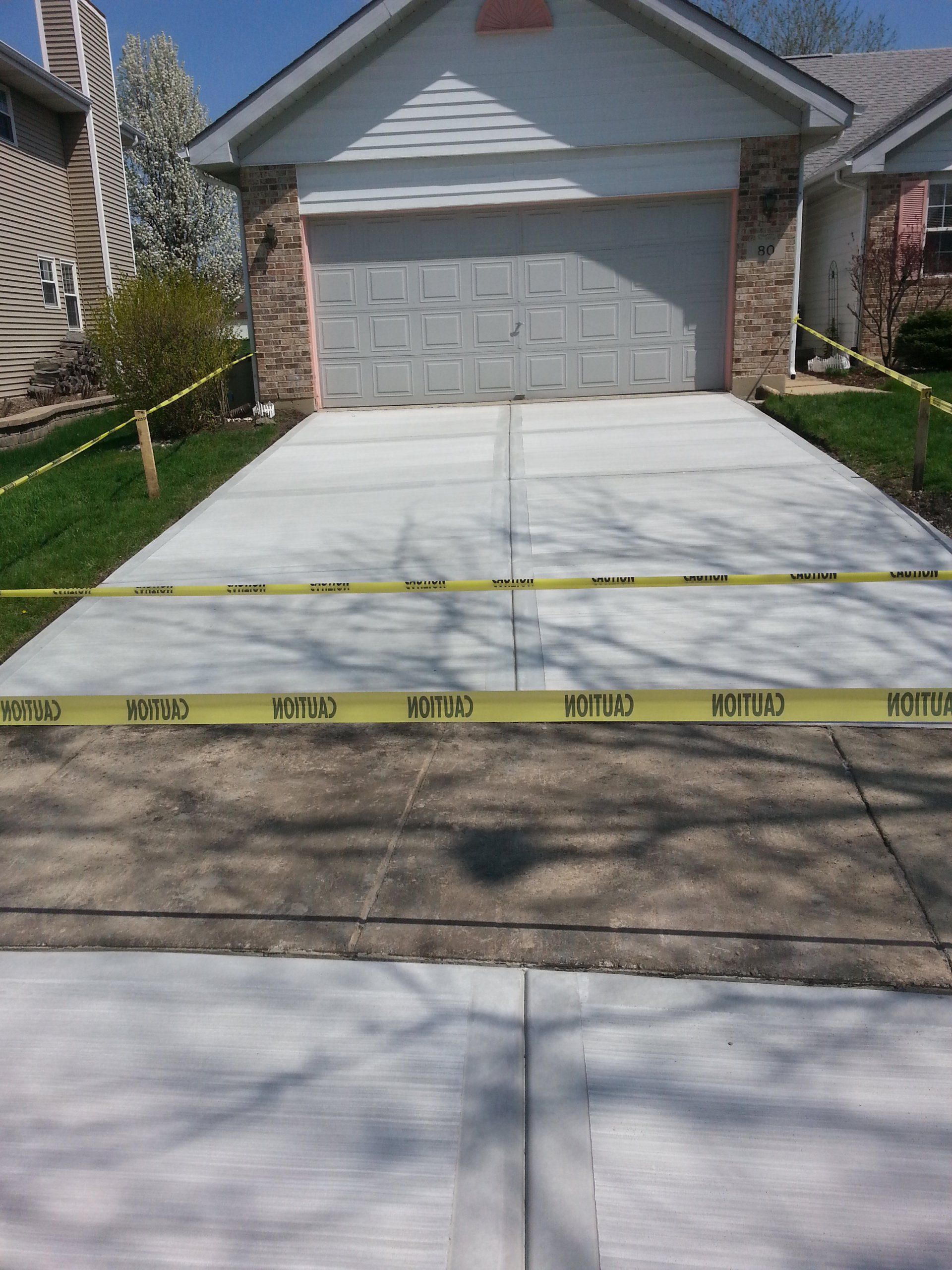 a concrete driveway in front of a house with yellow tape on it