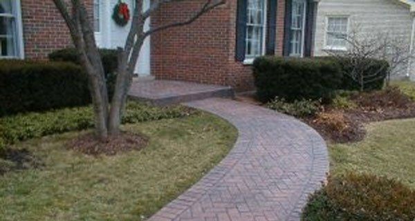 a brick walkway leading to the front door of a brick house .
