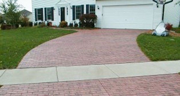 a red brick driveway leading to a white house