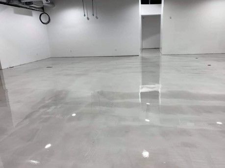 A large room with a shiny concrete floor and white walls.