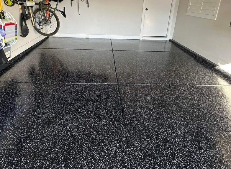 A bicycle is hanging on a wall in a garage with a black floor.