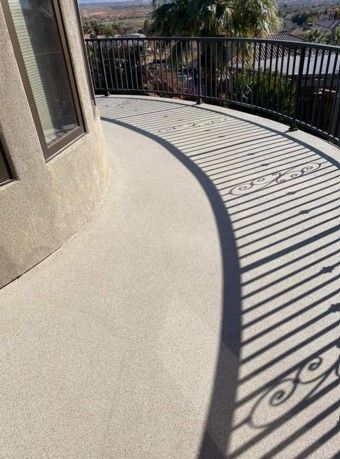 A balcony with a wrought iron railing and a shadow on the floor.