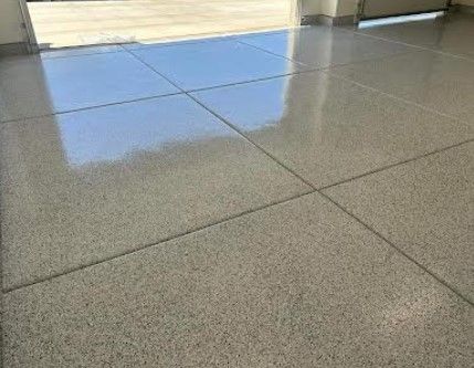 A close up of a tiled floor in a garage with a door in the background.