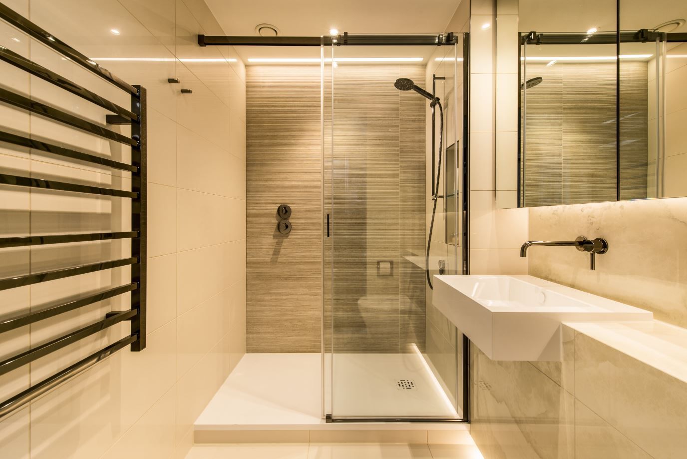 Modern bathroom with a glass shower, heated towel rack, and a floating sink.