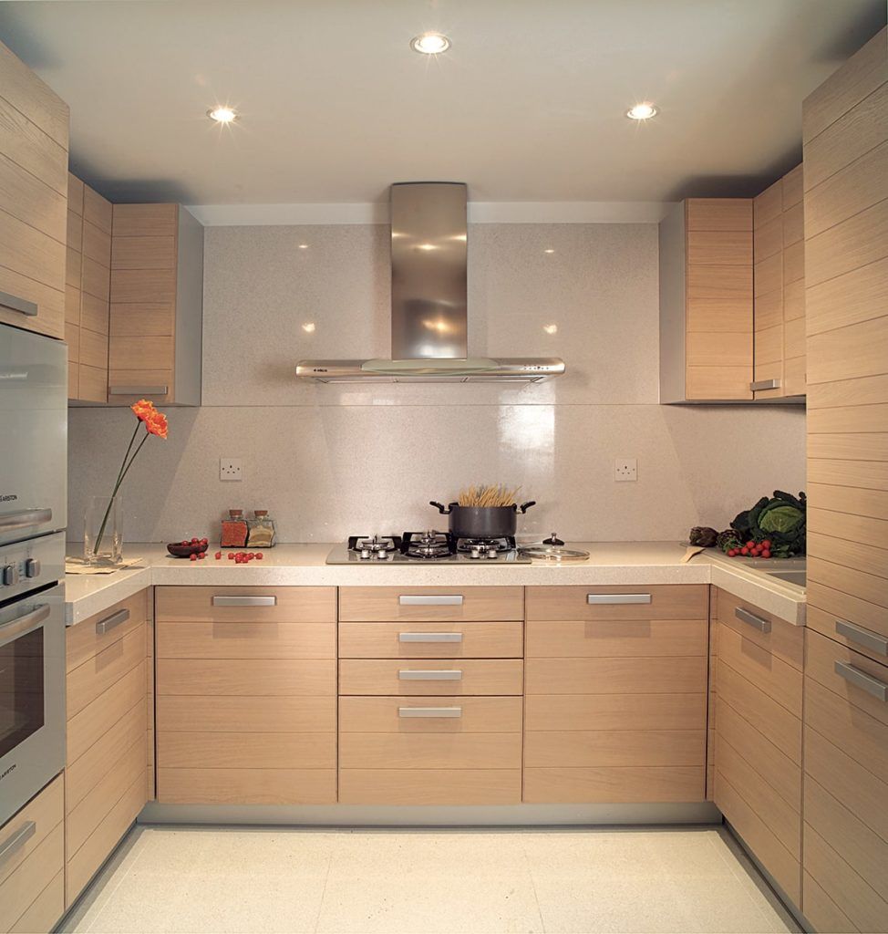 U-shaped modern kitchen with light wood cabinets, stainless steel appliances, and white countertops.