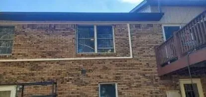 Brick house exterior with a deck and windows.