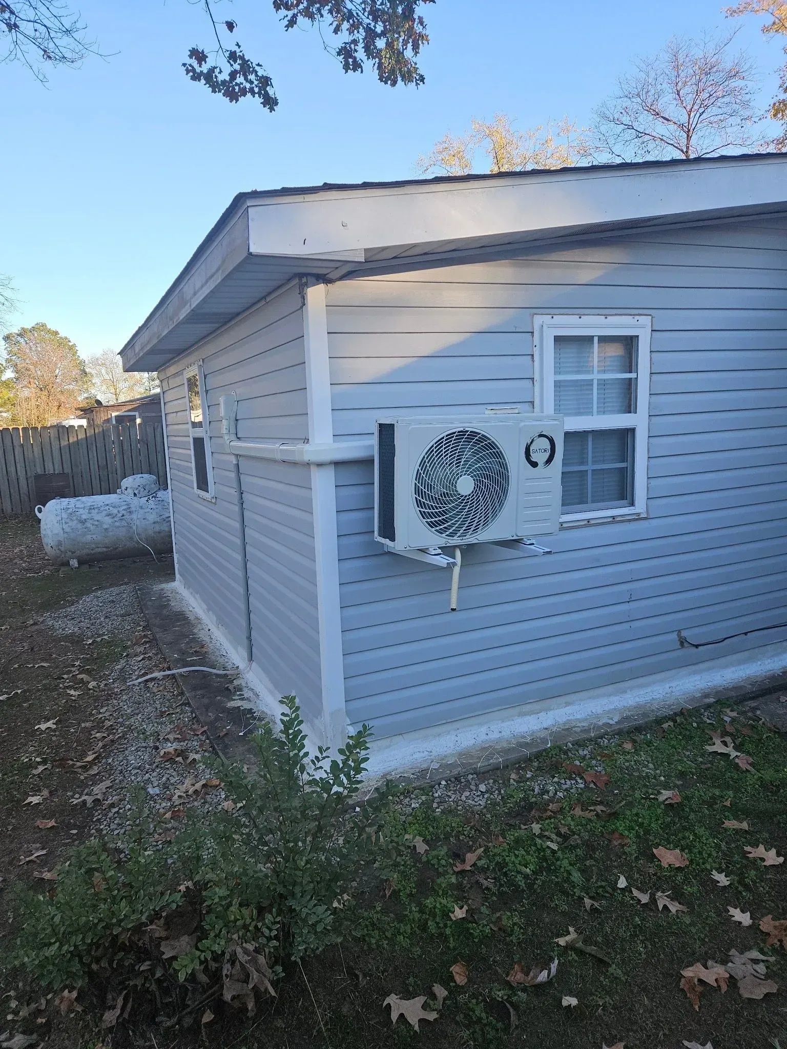 Light blue-sided shed with white trim; an air conditioning unit is mounted outside the right-side wall.