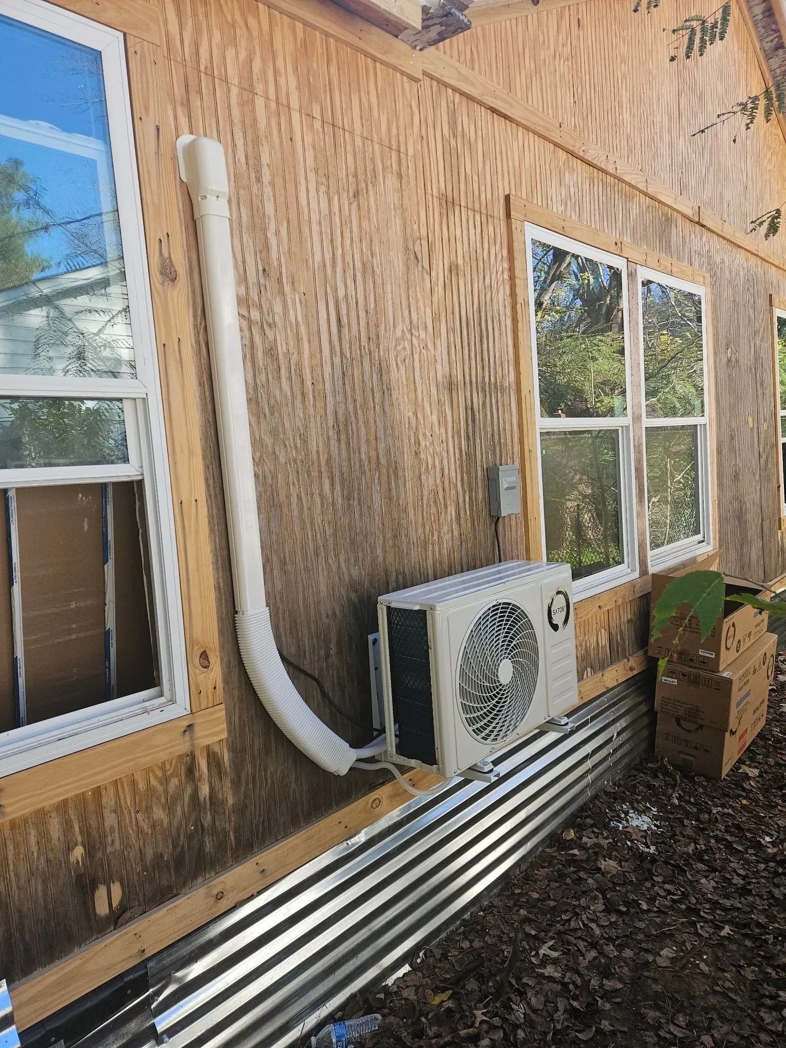 Exterior wall with window and air conditioning unit. Ductwork and corrugated metal siding visible.