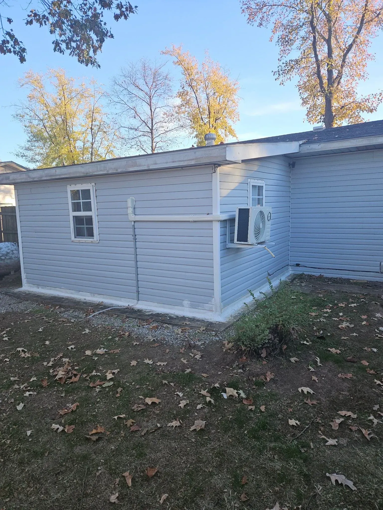 Light blue sided small building with air conditioning unit.