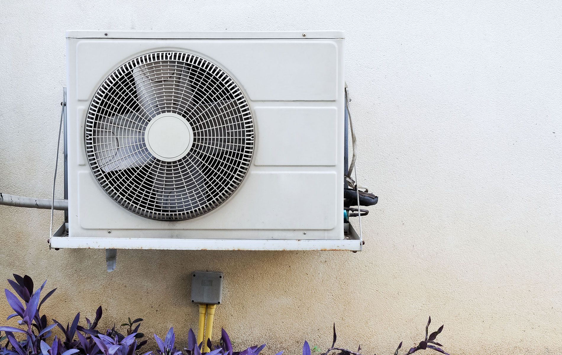 Air conditioning unit attached to a light-colored wall, with a large fan in front.