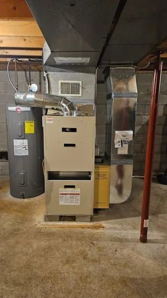 Furnace and water heater in a basement with ductwork.