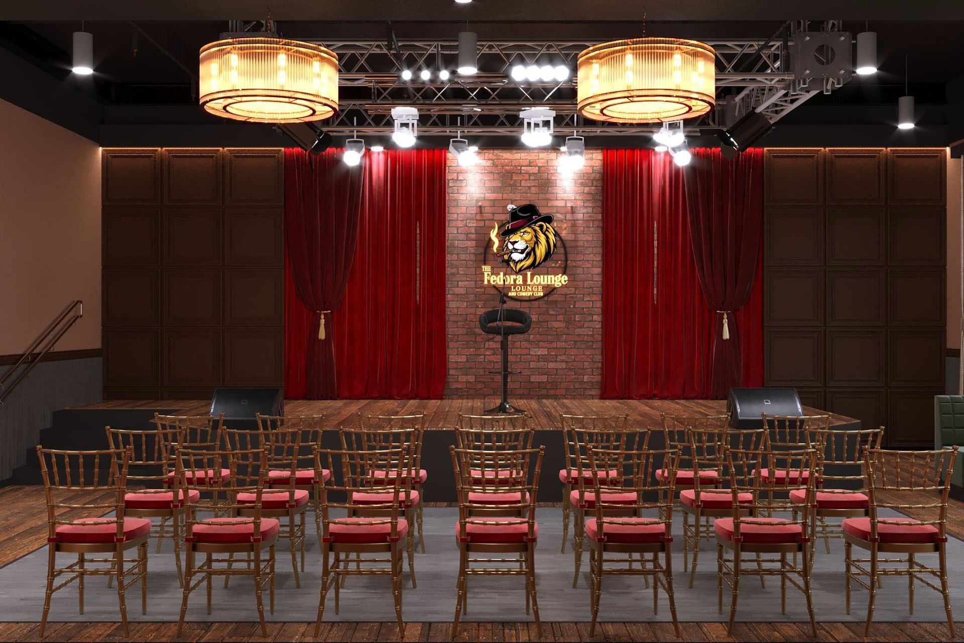 Interior of a performance venue with stage, red curtains, and rows of chairs. Two large lamps hang overhead.
