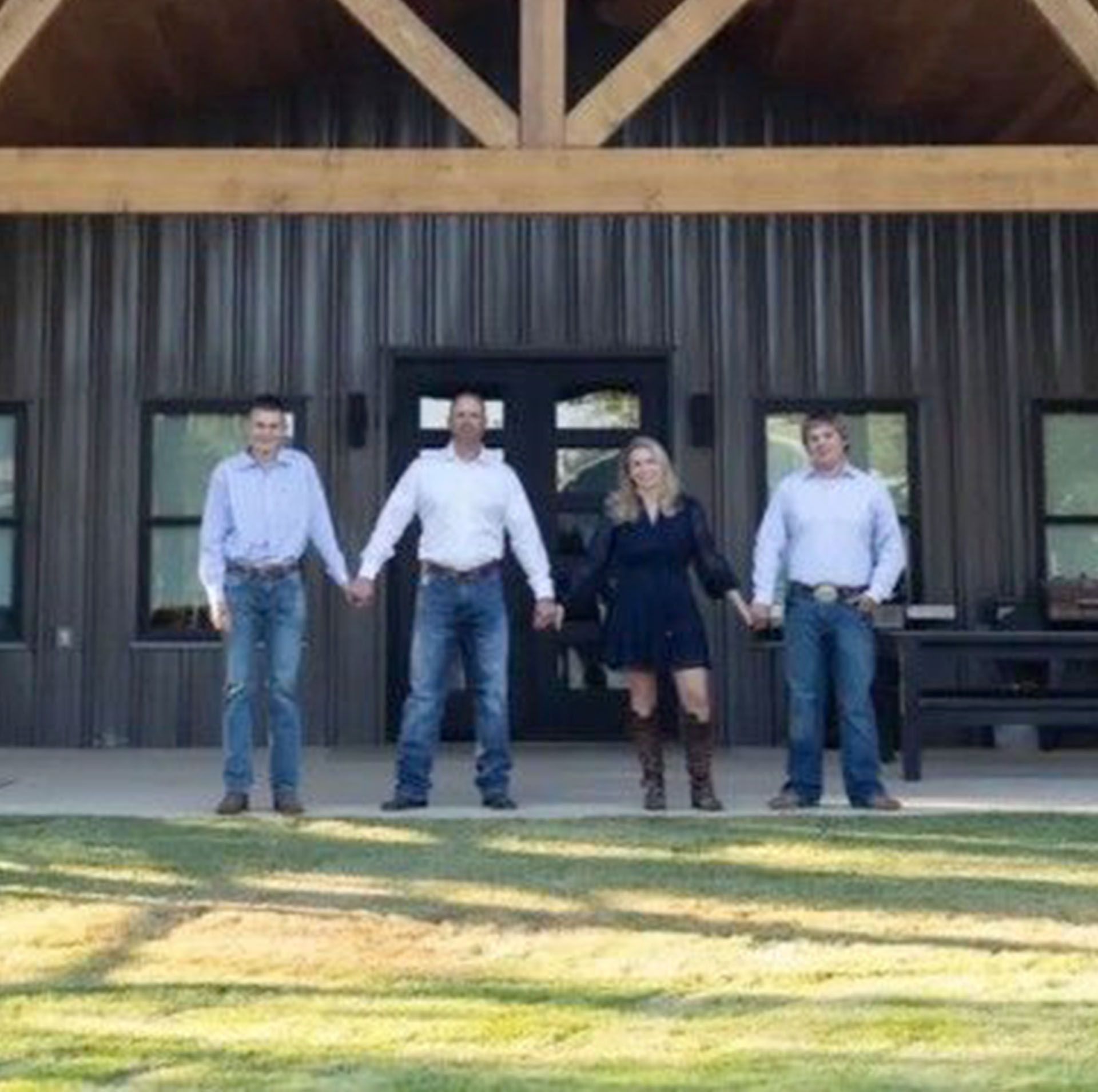 Family of four standing on porch, holding hands