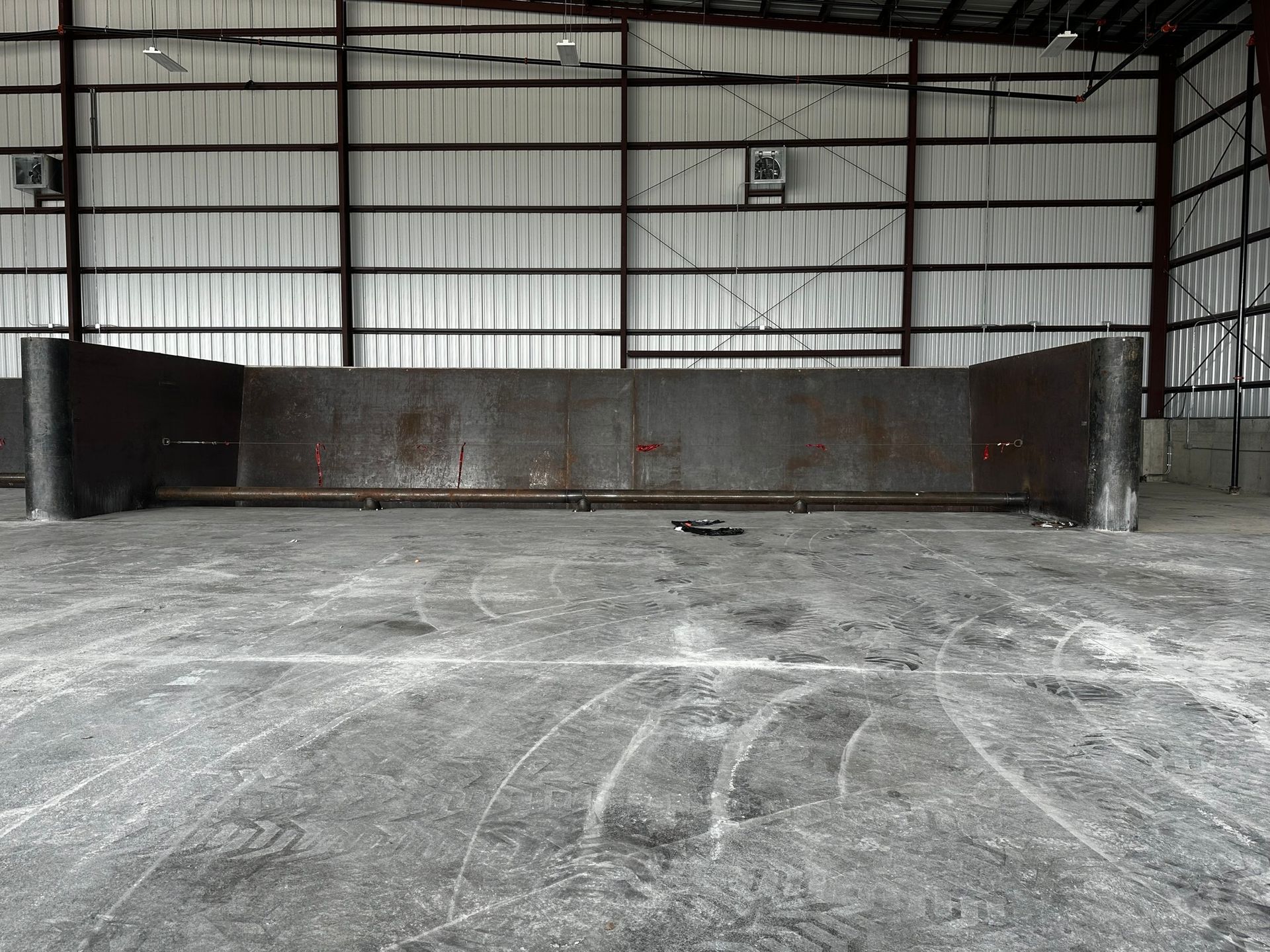 Empty metal building with a large, rusted metal structure in the center; gray floor.