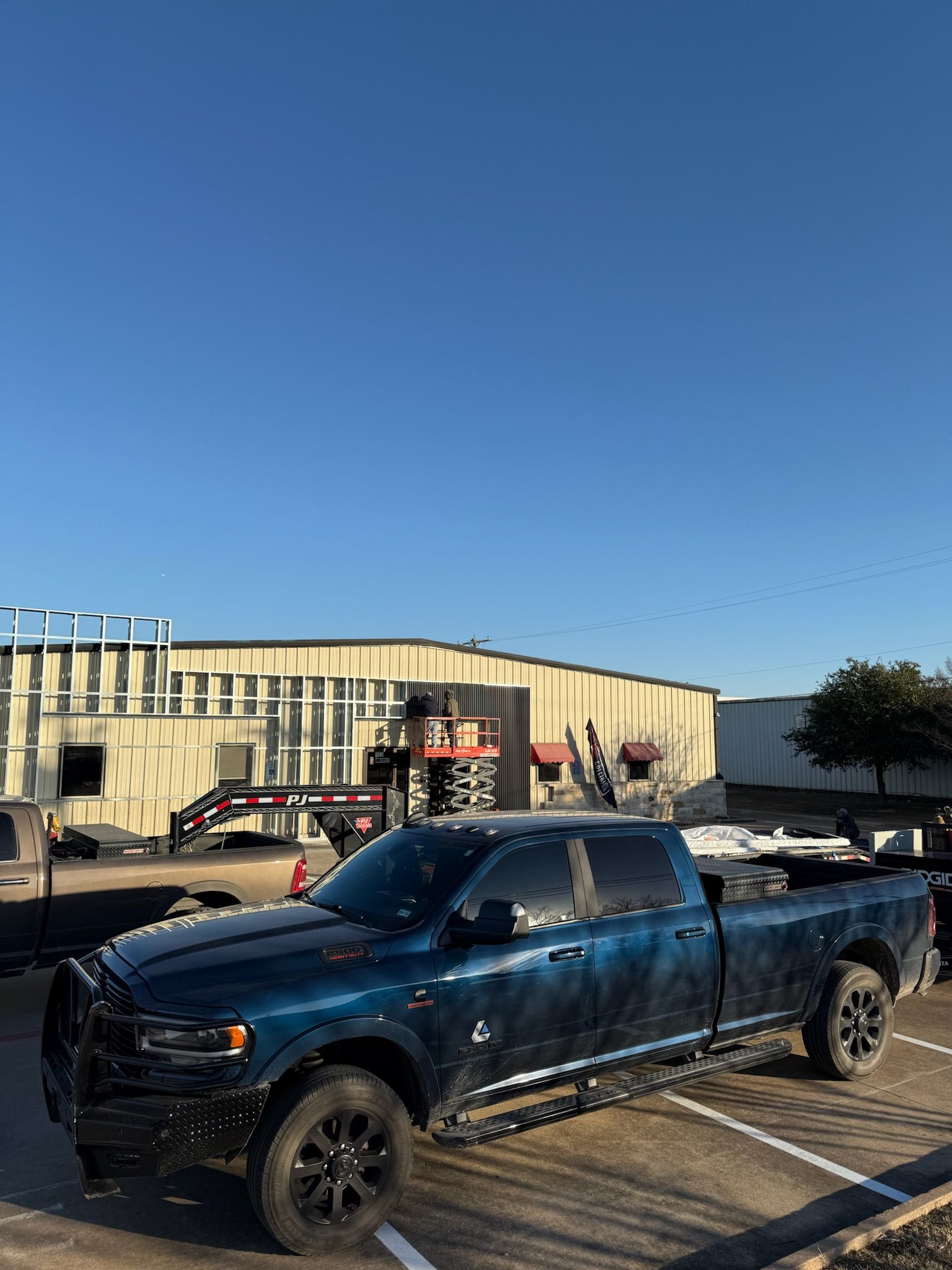 Dark blue pickup truck parked; construction site in background, blue sky.