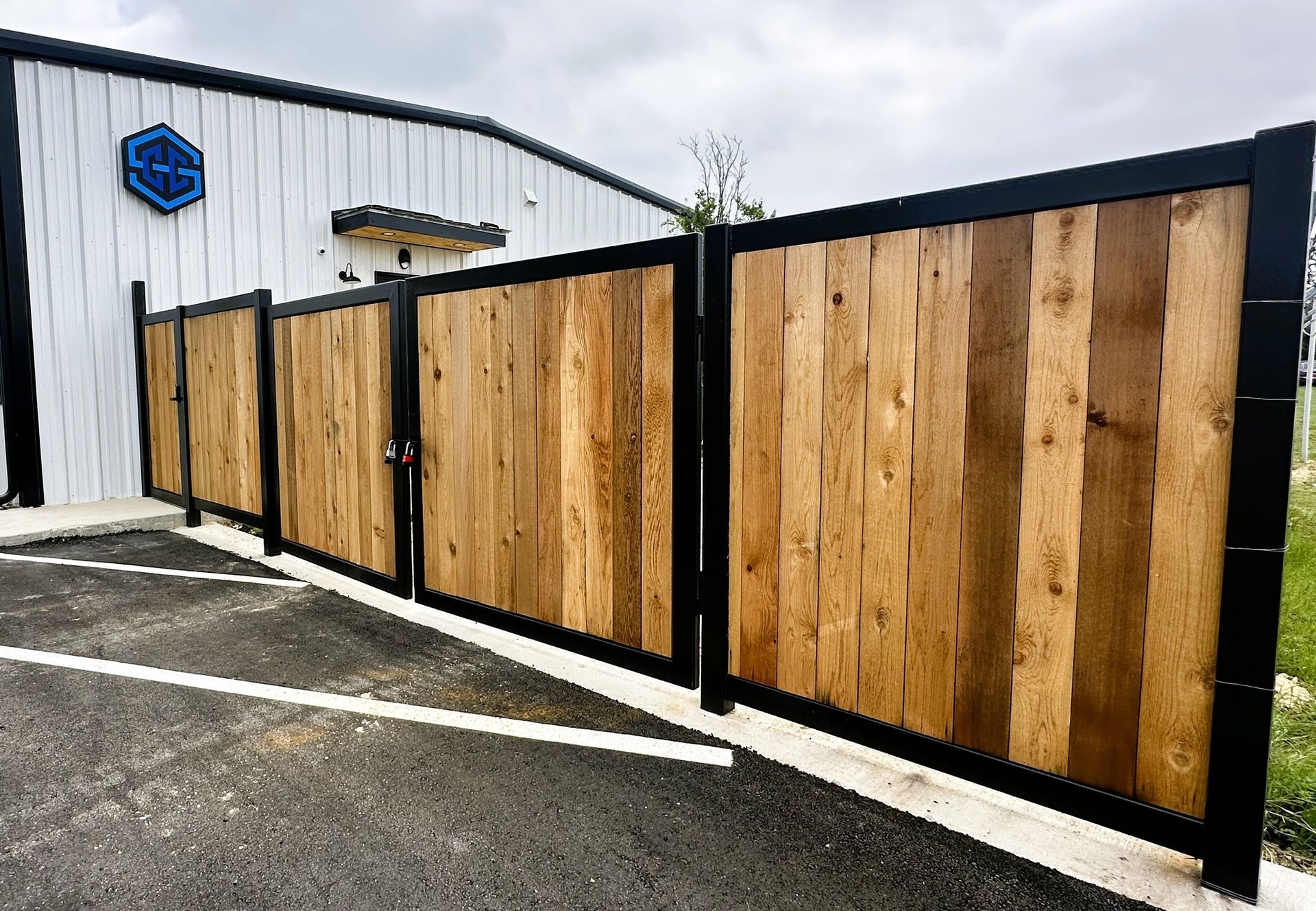 Wooden fence with black metal frame outside a building with a blue logo.