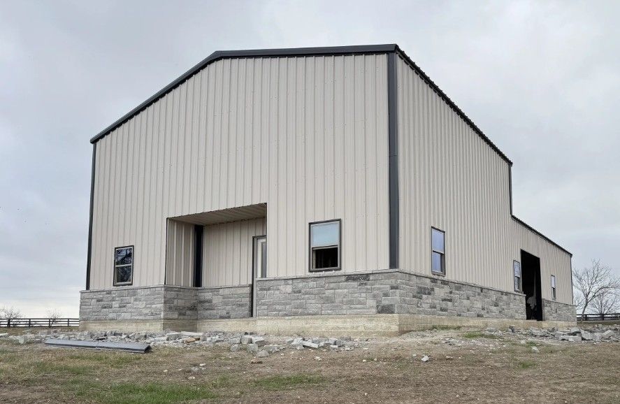 Metal building with stone base; windows, and a covered porch. Overcast sky.