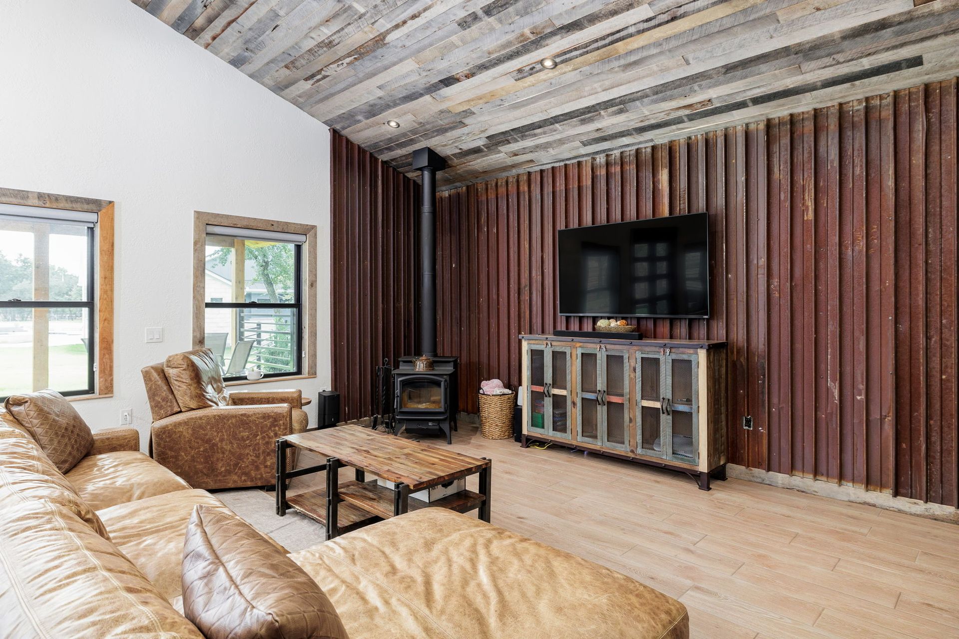 Living room with a sectional sofa, wood-paneled walls, fireplace, and TV.