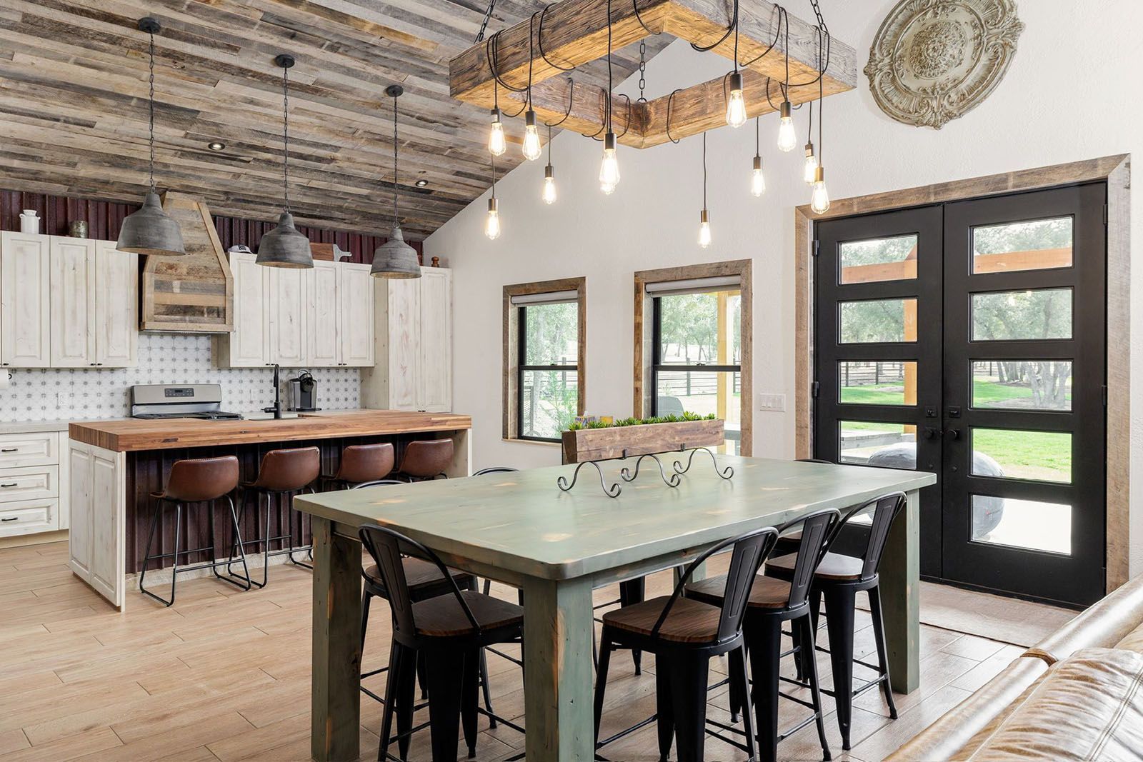 Rustic kitchen and dining area with wooden accents, light fixtures, and a large table