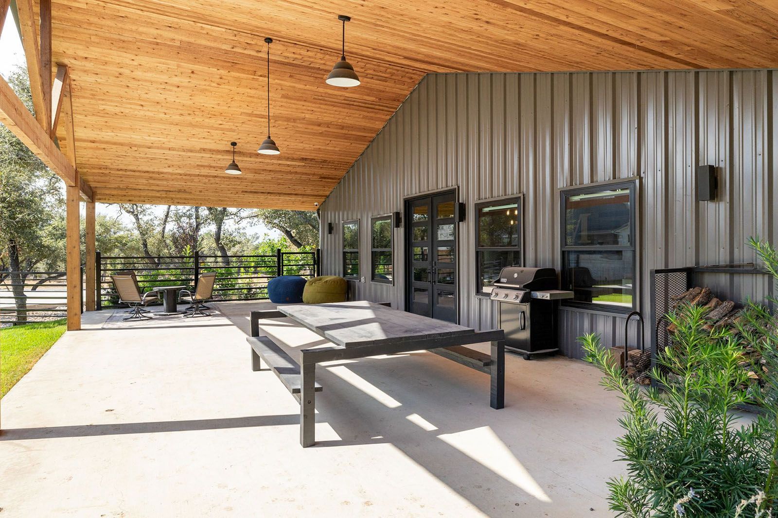 Covered outdoor patio with table, grill, and metal siding on a building