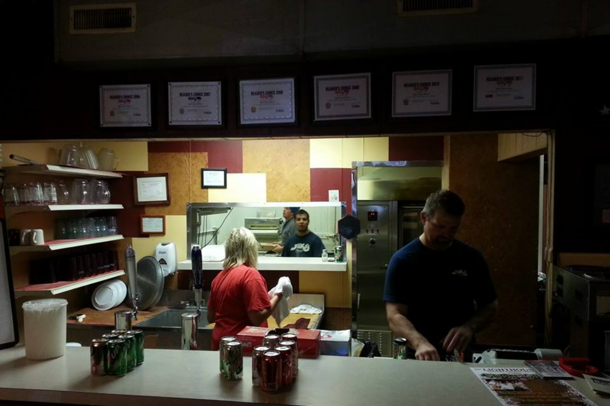Restaurant kitchen with three staff members working behind a counter.