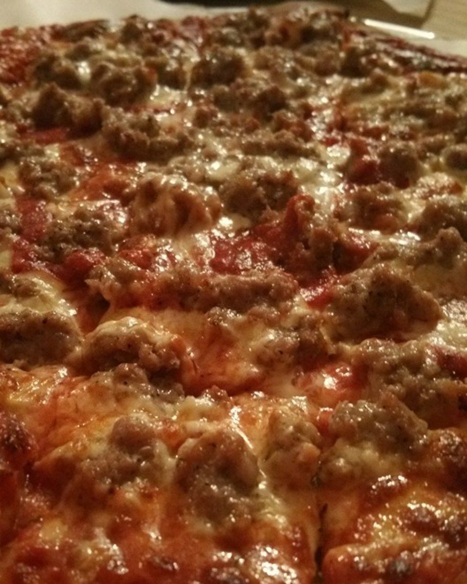 Close-up of a pizza with sausage topping, tomato sauce, and melted cheese.
