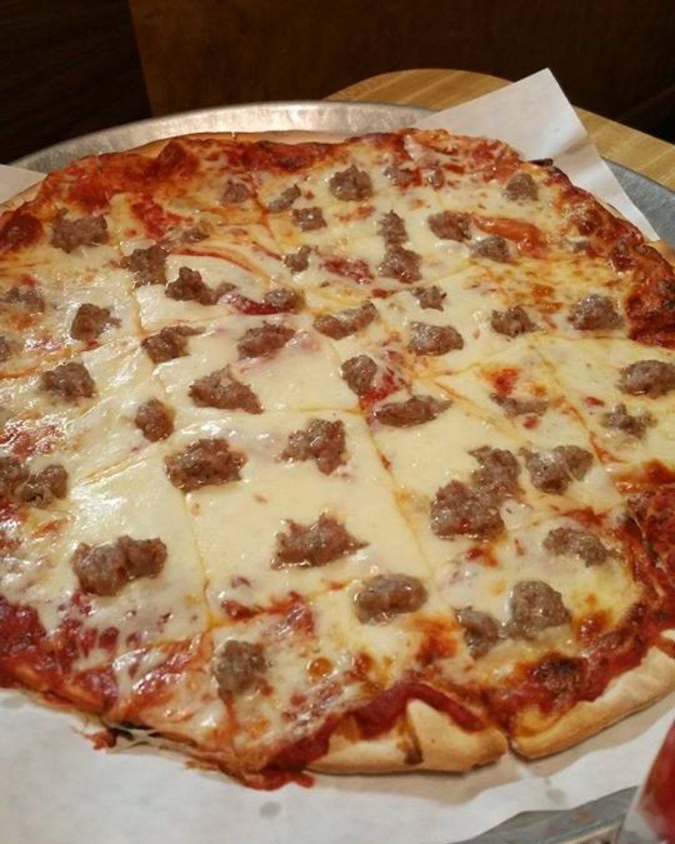 Pizza with sausage, mozzarella cheese, and tomato sauce, on a metal tray.