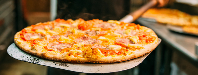 Pizza being removed from the oven on a pizza peel.