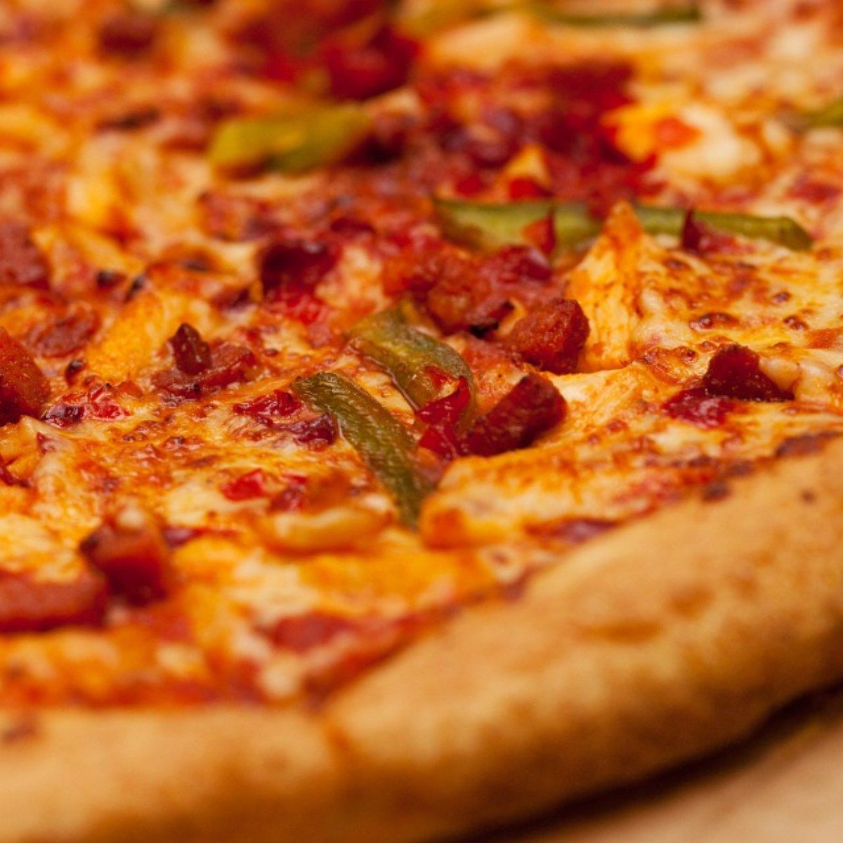 Close-up of a pizza with cheese, peppers, and sausage.