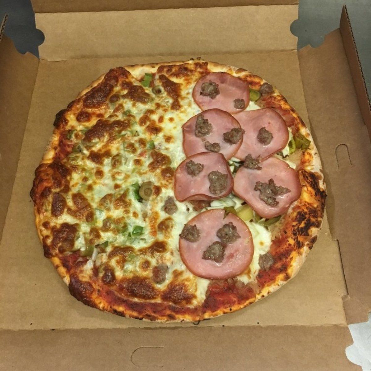 Pizza with ham and green peppers in a cardboard box.