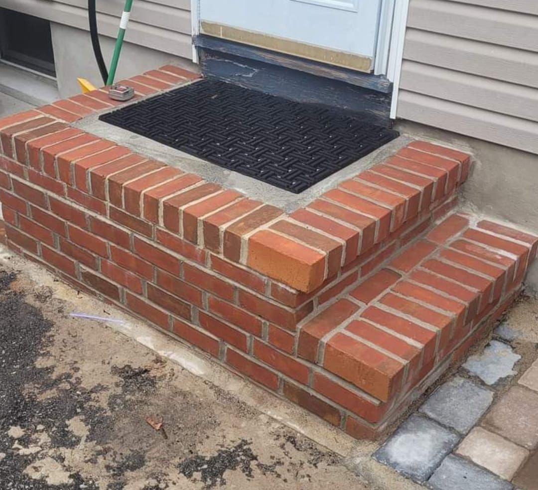 Brick steps leading up to a doorway with a black mat.