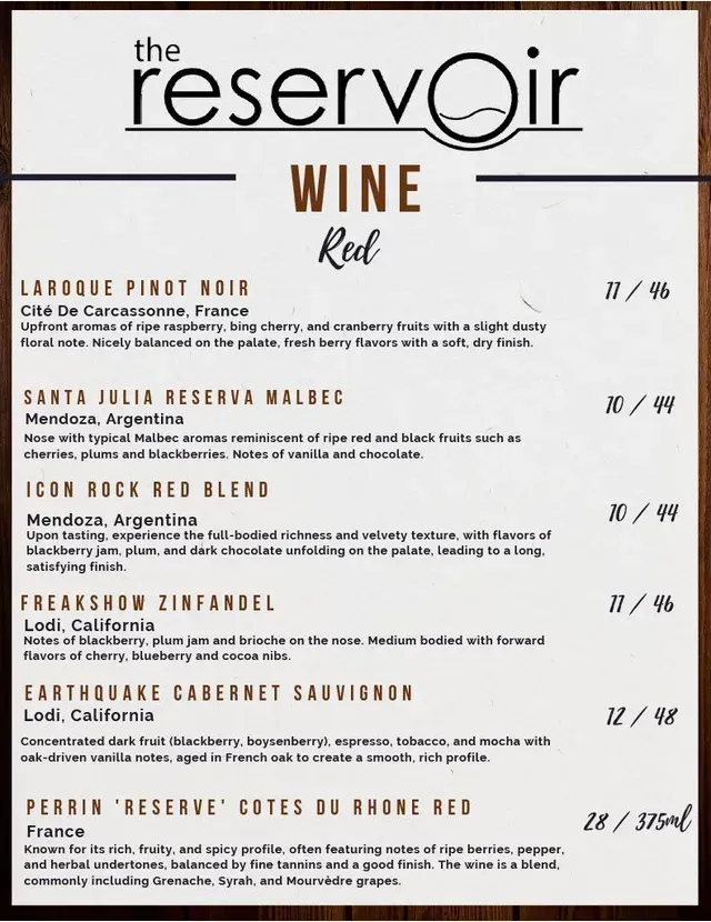 The Reservoir wine menu listing red wines, prices, and tasting notes on a white sign