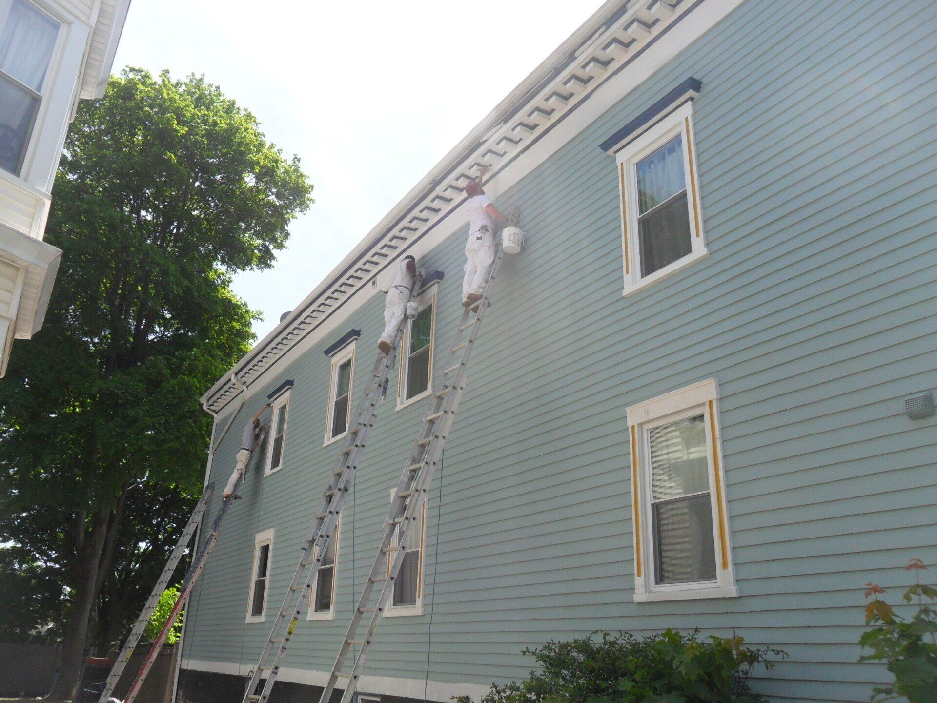 A man on a ladder paints the side of a building