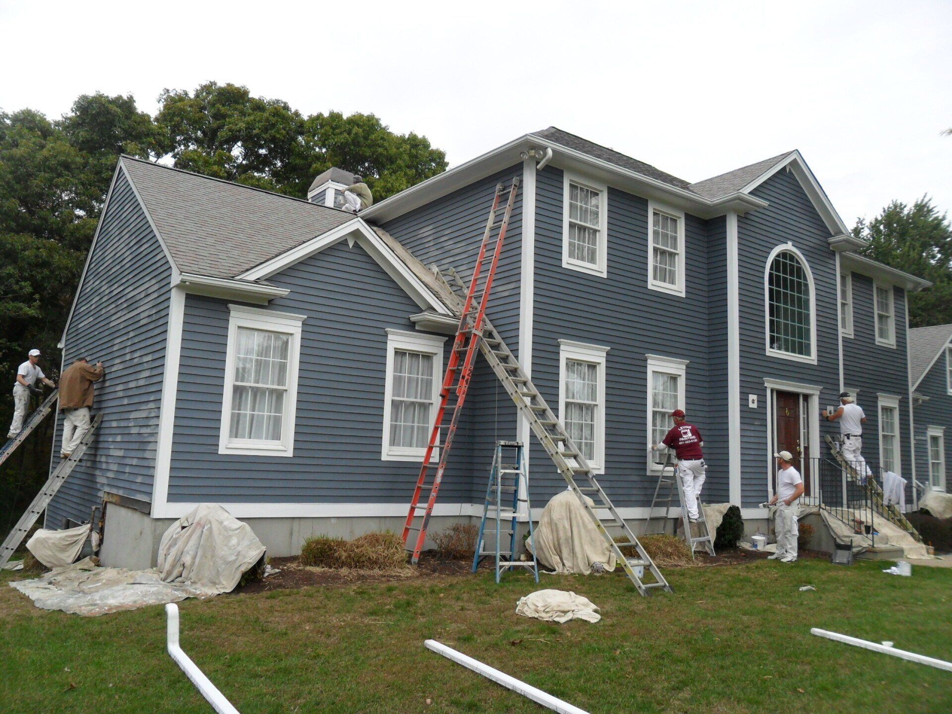 A group of people are painting a large blue house