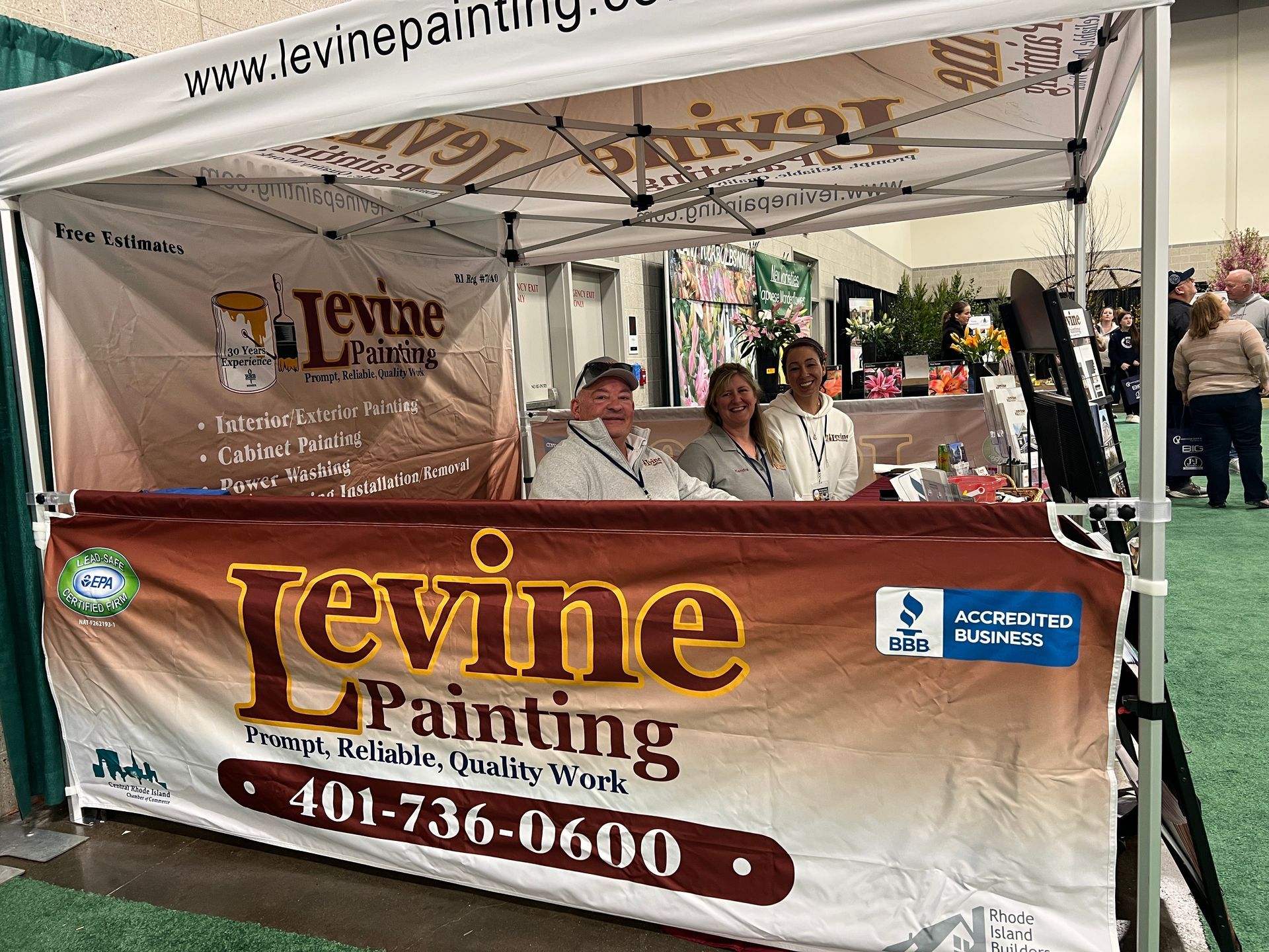 A group of people standing behind a levine painting tent