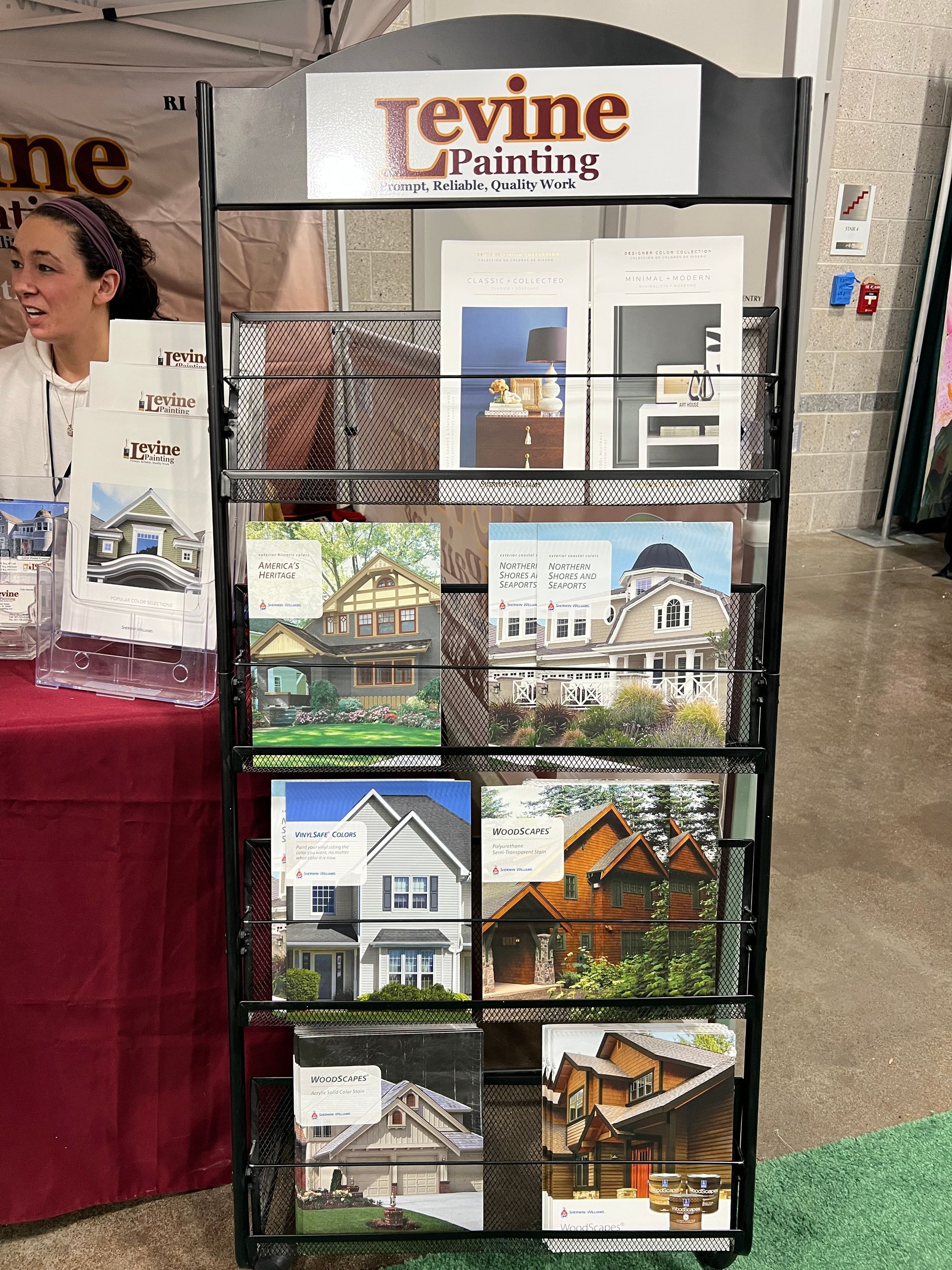 A woman is standing in front of a levine painting display.