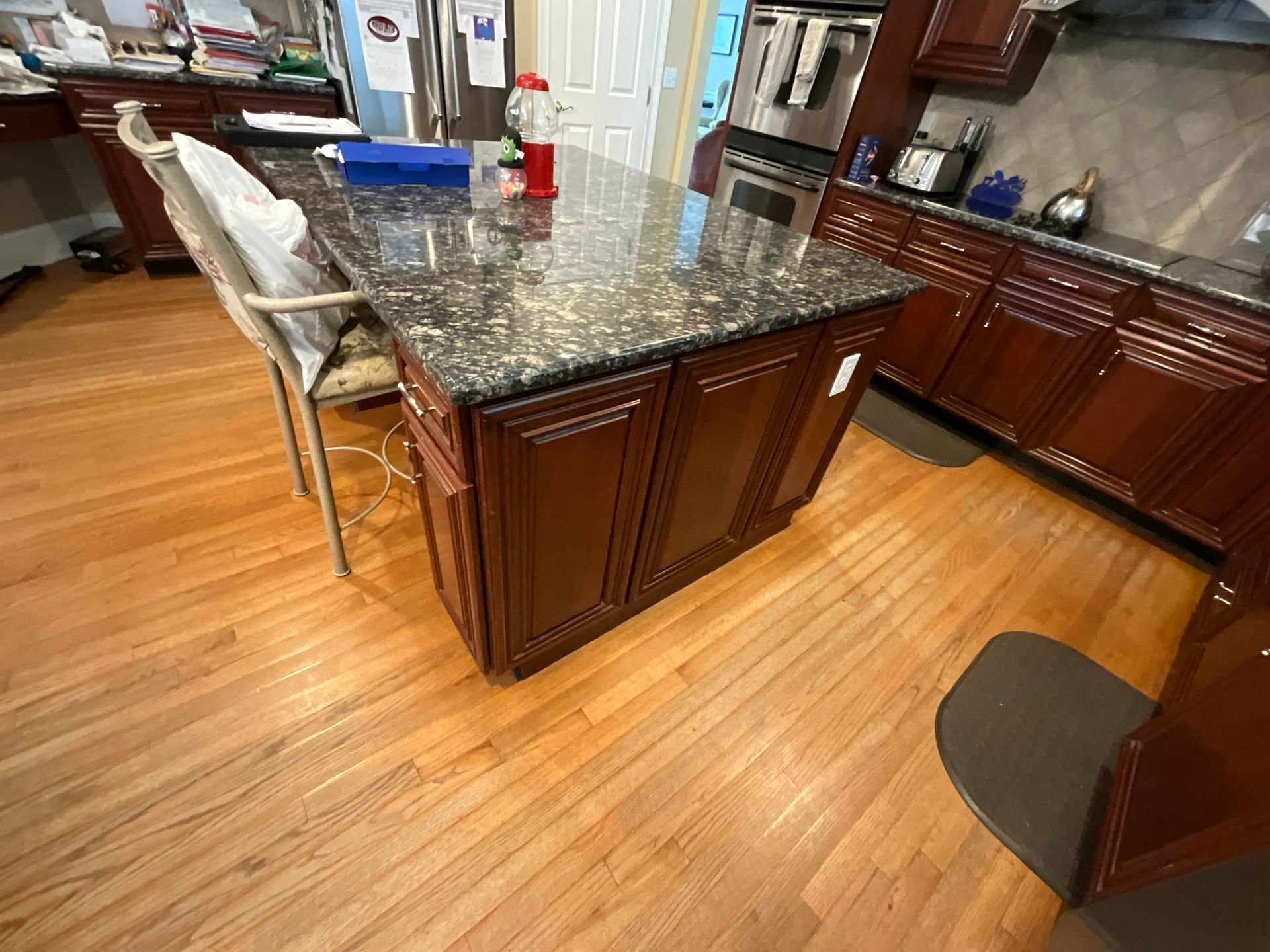 Kitchen with dark brown cabinets, a granite island, and hardwood floors.
