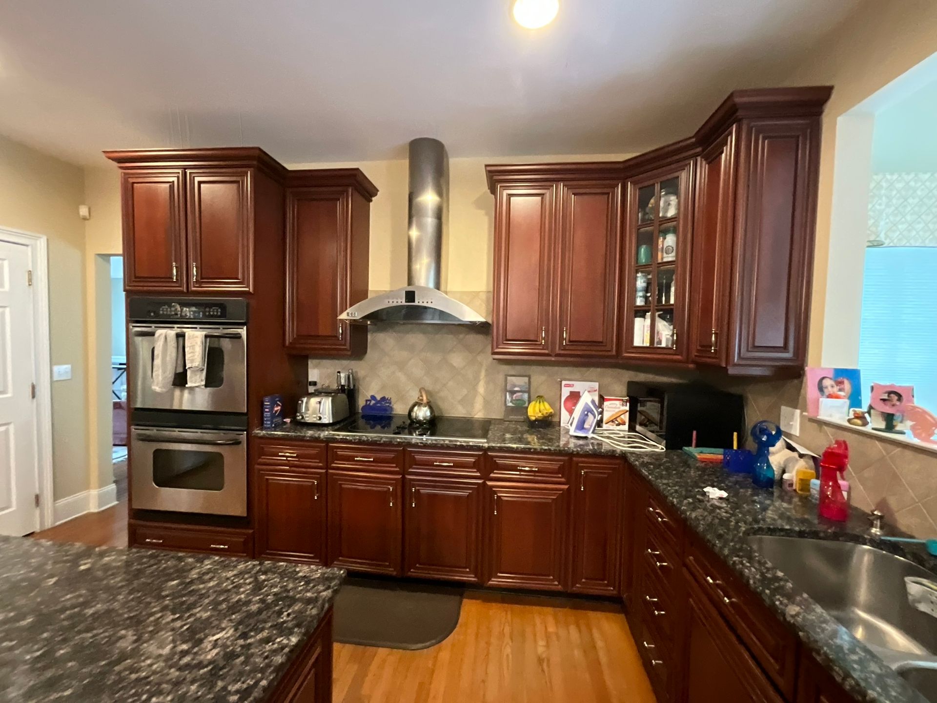 A kitchen with dark wood cabinets, stainless steel appliances, and a black speckled countertop.