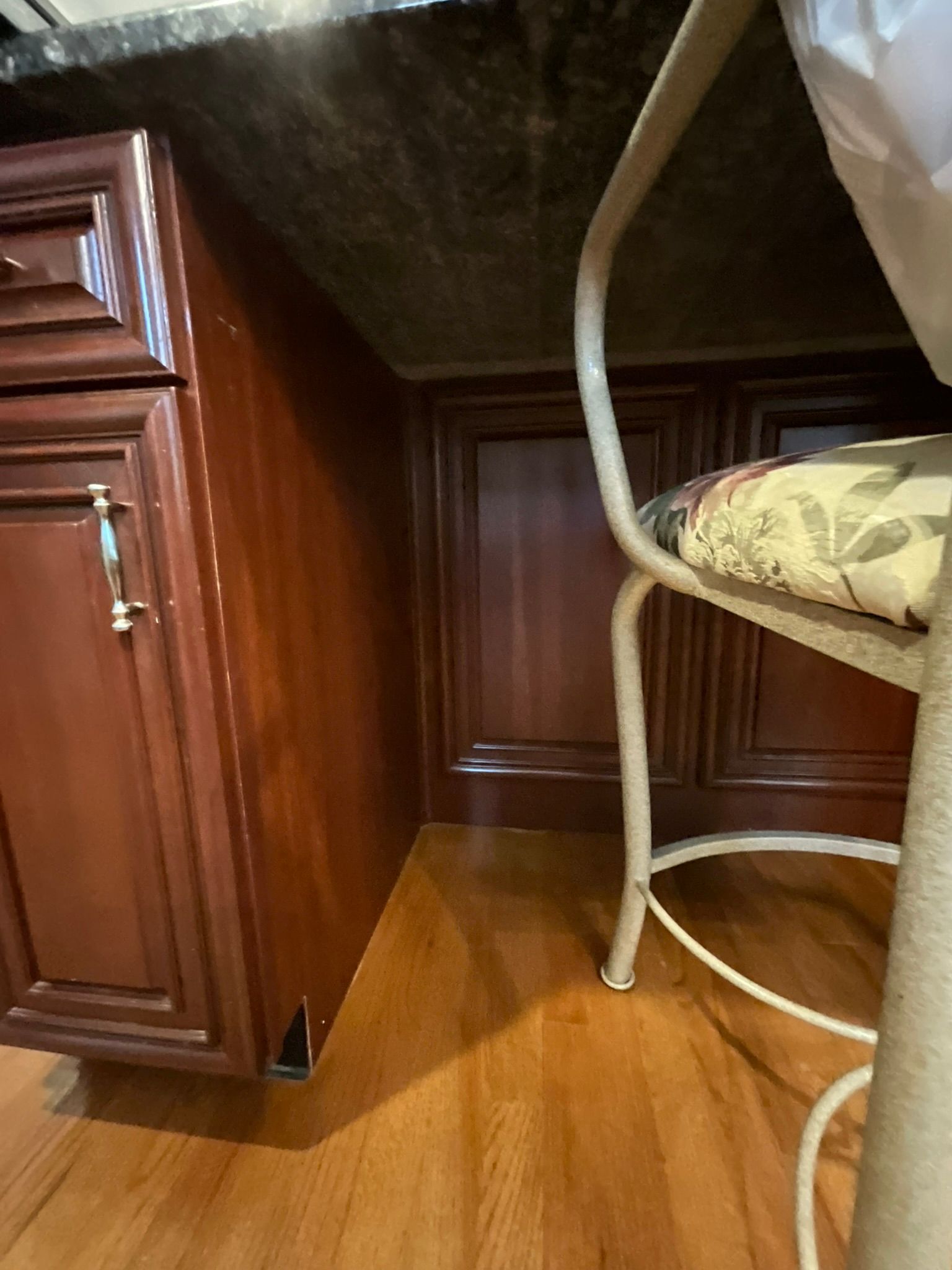 Brown kitchen cabinets with a wood floor. A white chair is present.