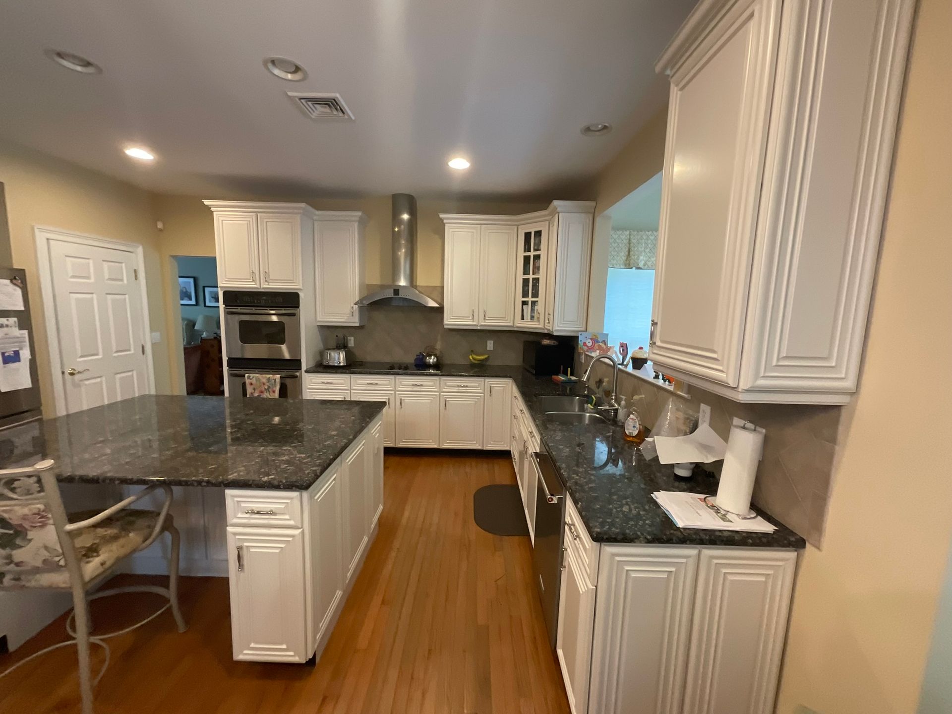 Kitchen with white cabinets, granite countertops, stainless steel appliances, and wooden floor.