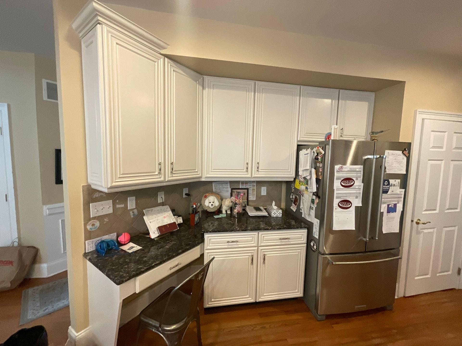White kitchen cabinets and stainless steel refrigerator in a kitchen corner.