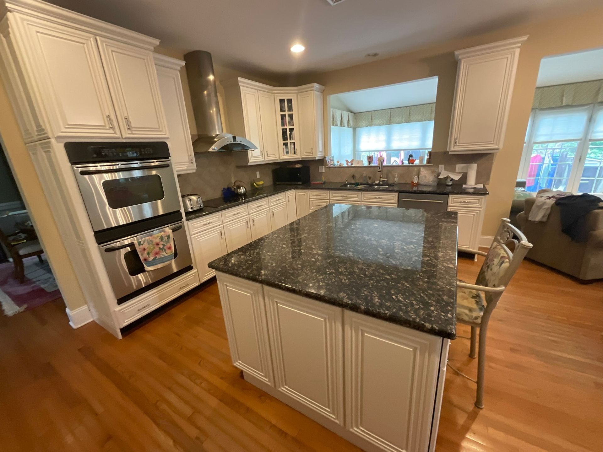 Kitchen with white cabinets, granite countertops, island, and stainless steel appliances.