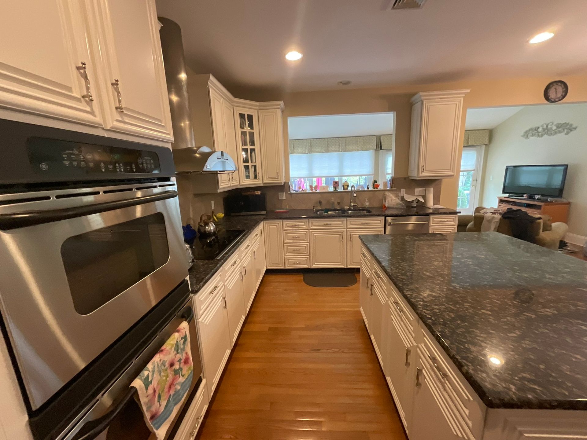 Kitchen with white cabinets, dark countertops, and wooden floor. Includes oven and island.