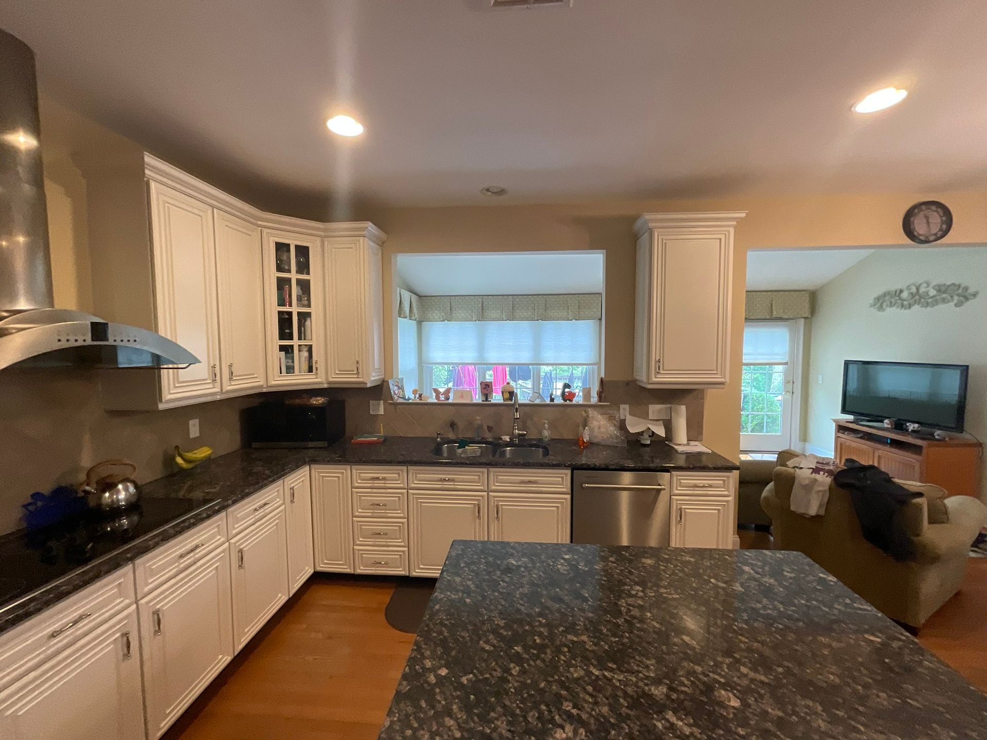 Kitchen with white cabinets, black countertops, stainless steel appliances, and a dark island.