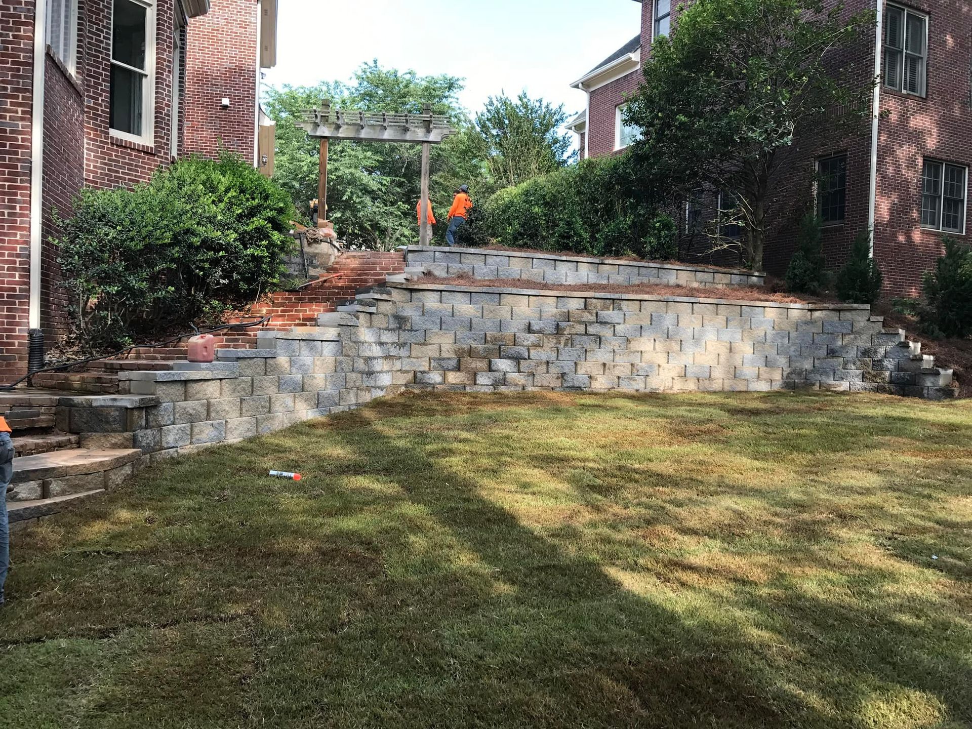 A brick wall is being built in the backyard of a house.