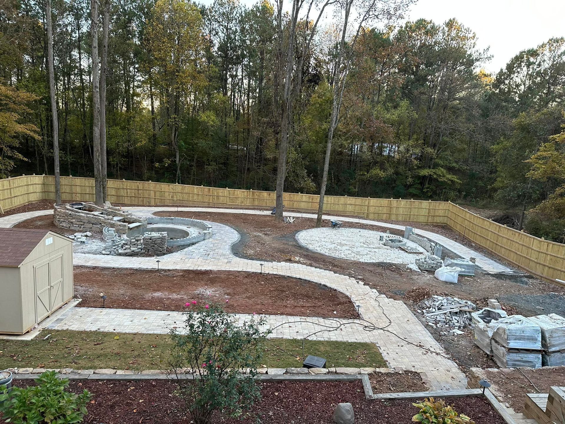 A large backyard with a fence and a swimming pool under construction.