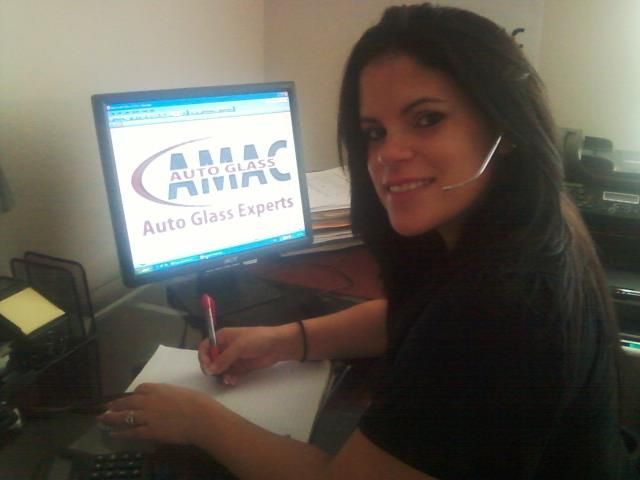 A woman sits at a desk in front of a computer screen that says amac auto glass experts